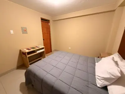 a bedroom with a bed and a small table at Tres Cruces Private Rooms in Cusco