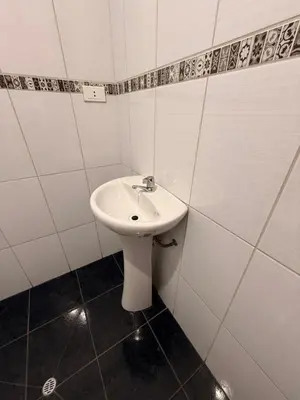 a white sink in a bathroom with white tiles at Tres Cruces Private Rooms in Cusco