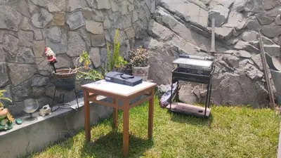 a table with a grill next to a stone wall at Casa Portada del Sol La Molina in Lima