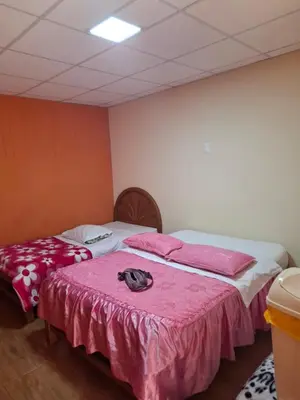 two beds in a room with pink sheets at Hospedaje Las Brisas in Churín