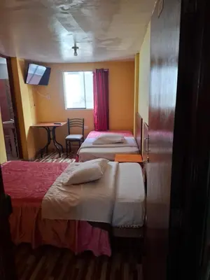 a hotel room with two beds and a table at Hospedaje Las Brisas in Churín