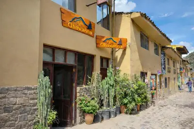 a building with plants outside of it on a street at Qhawarina Hostel Ollantaytambo in Ollantaytambo
