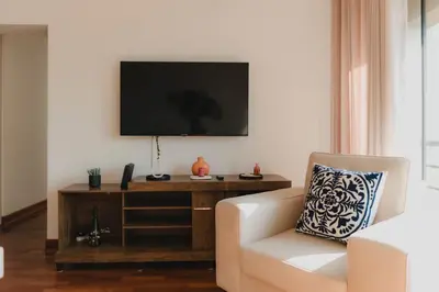 a living room with a white chair and a television at Recavarren 3 Dormitorios by Casa Miraflores - Wifi - Washer - Hot Water in Lima