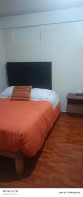 a bed with an orange comforter in a room at AMARU Palace in Machu Picchu
