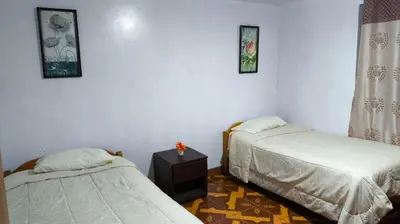 a room with two beds and a table in it at Victoria home san blas in Cusco