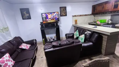 a living room with couches and a bar with a television at Victoria home san blas in Cusco