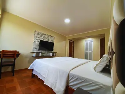 a bedroom with a white bed and a tv at Hotel Leal in Ayacucho