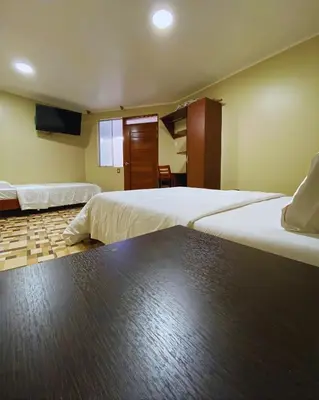 a hotel room with two beds and a television at Hotel Leal in Ayacucho