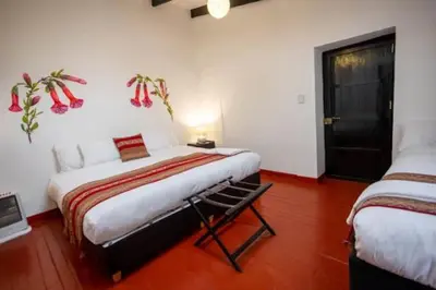 a bedroom with two beds and a black door at San Blas Plaza Hotel in Cusco