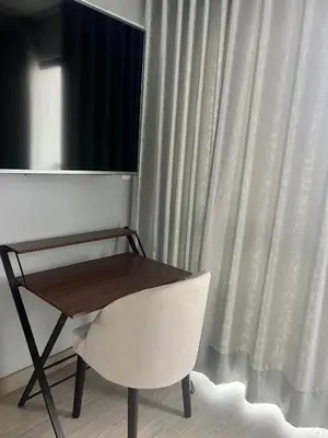 a wooden table and a white chair next to a window at Departamento cerca al mar con terraza panoramica in Lima
