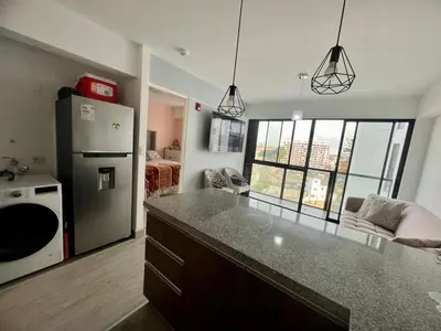 a kitchen with a refrigerator and a counter top in a room at Departamento cerca al mar con terraza panoramica in Lima