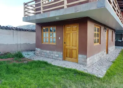a small house with a wooden door and a porch at Wasi Wasi in Urubamba