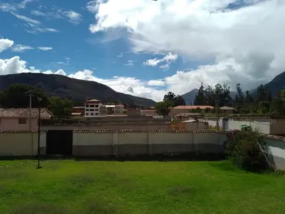 a green yard with mountains in the background at Wasi Wasi in Urubamba