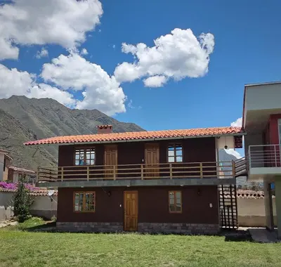 a house with a balcony and mountains in the background at Wasi Wasi in Urubamba