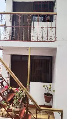 a building with a balcony with a table and flowers at San Blas B&B in Cusco
