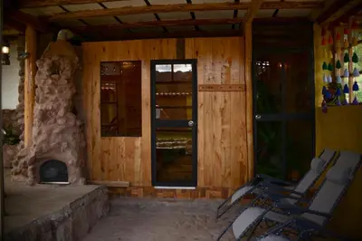 a room with a fireplace and chairs in front of a house at Unu Samay Lodge in Urubamba