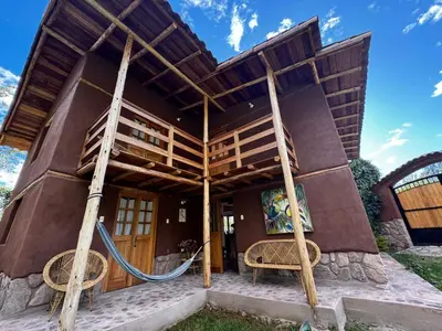 a house with a wooden roof and two chairs at Casa Nuestra in Urubamba