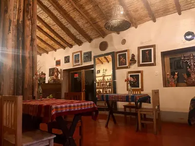 a room with two tables and chairs and a room with pictures at hospedaje Illary in Quinua