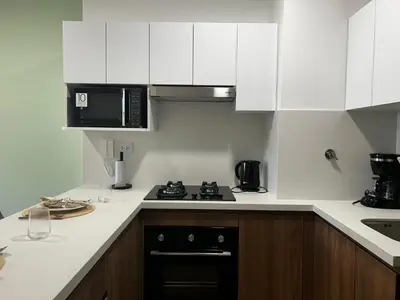 a white kitchen with a stove and a microwave at Loft Bohemio a 1 cuadra de plaza Barranco in Lima