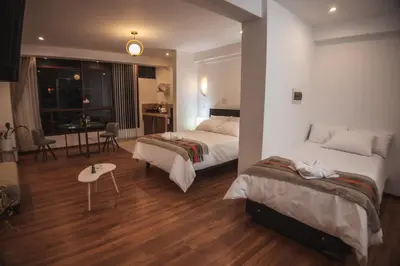 a hotel room with two beds and a table at Florez de la Villa Apart Hotel in Cusco