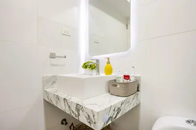 a white bathroom with a sink and a mirror at Barranco apartment facing the ocean in Lima