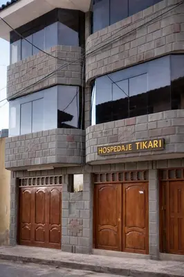 a building with two wooden doors and windows at Hospedaje Tikari in Chinchero