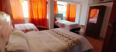 a hotel room with two beds and orange curtains at Hospedaje Tikari in Chinchero