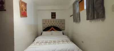a small white bedroom with a bed in it at Hospedaje Tikari in Chinchero