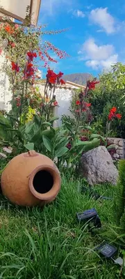 a flower garden with a pot in the grass at Florez de la Villa Apartments in Urubamba