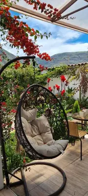 a wicker chair sitting on a patio with flowers at Florez de la Villa Apartments in Urubamba