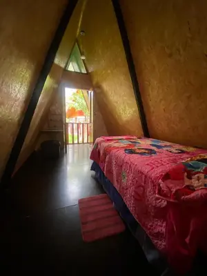 a bedroom with a red bed in a attic at Cabañas Vivenciales La Colina in Oxapampa