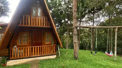 a house with a porch and a swing at Cabañas Vivenciales La Colina in Oxapampa