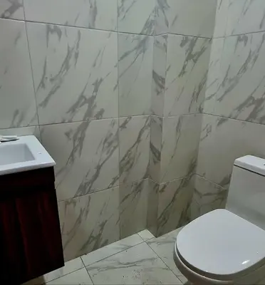a bathroom with a white toilet and a marble wall at Cusco Apartment Prime Location in Cusco