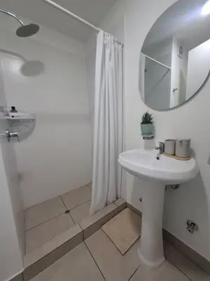 a white bathroom with a sink and a mirror at Cómoda habitación con TV a 20 min del aeropuerto in Lima