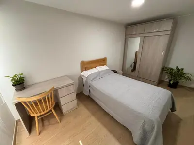 a bedroom with a bed and a desk with a chair at Amplia habitación con baño propio a 20 min del aeropuerto in Lima