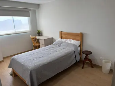 a bedroom with a bed and a table and a window at Amplia habitación con baño propio a 20 min del aeropuerto in Lima