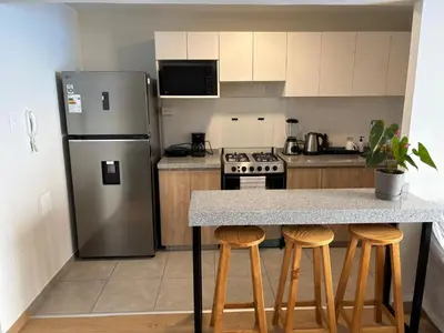 a kitchen with a stainless steel refrigerator and bar stools at Amplia habitación con baño propio a 20 min del aeropuerto in Lima