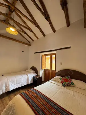 a bedroom with two beds in a room with wooden ceilings at plaza inn in Ollantaytambo