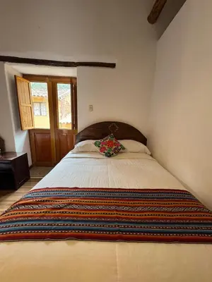 a bedroom with a large bed with a blanket on it at plaza inn in Ollantaytambo