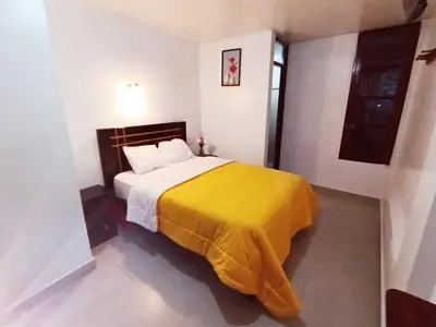 a bedroom with a bed with a yellow blanket on it at Destinos Peru Inn - Destinos in Machu Picchu