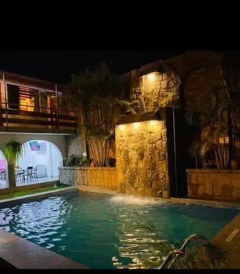 a swimming pool at night with a stone wall at Inka Palace Resort in Santa Eulalia