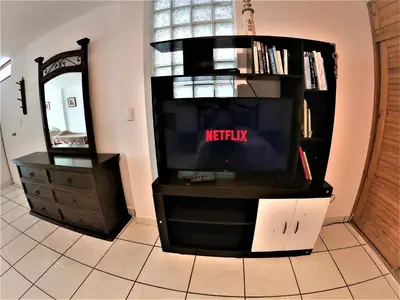 a tv sitting on a entertainment center with a mirror at Waves Surf Camp Peru in Punta Hermosa