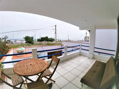 a balcony with chairs and a table and a couch at Waves Surf Camp Peru in Punta Hermosa