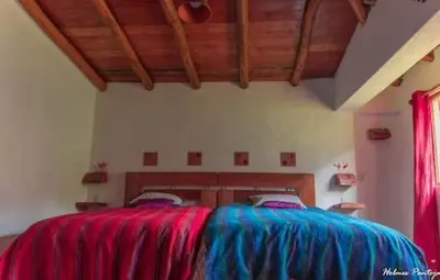 a bedroom with a bed with blue and red sheets at Birds Hotel Molino in Ollantaytambo