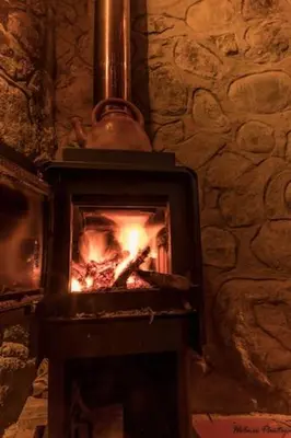 a stone fireplace with a fire in it at Birds Hotel Molino in Ollantaytambo