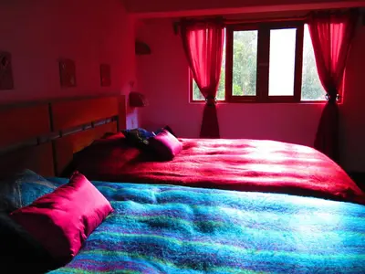 a bedroom with a large bed with red sheets and a window at Birds Hotel Molino in Ollantaytambo