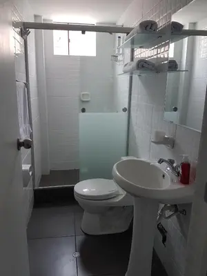 a white bathroom with a toilet and a sink at Lima Flats in Lima