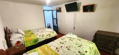 a small room with two beds and a television at Hostel Imperial BACKPACKER in Cusco