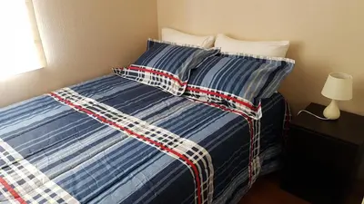 a bed with a blue and white comforter and pillows at Lima Flats 2 in Lima