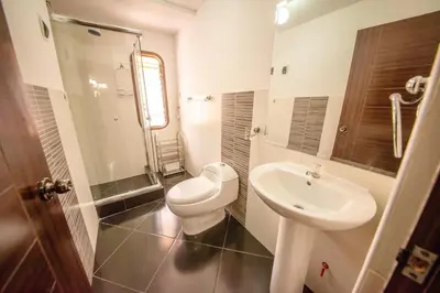 a white bathroom with a toilet and a sink at Allincay Cusco Apart Hotel in Cusco